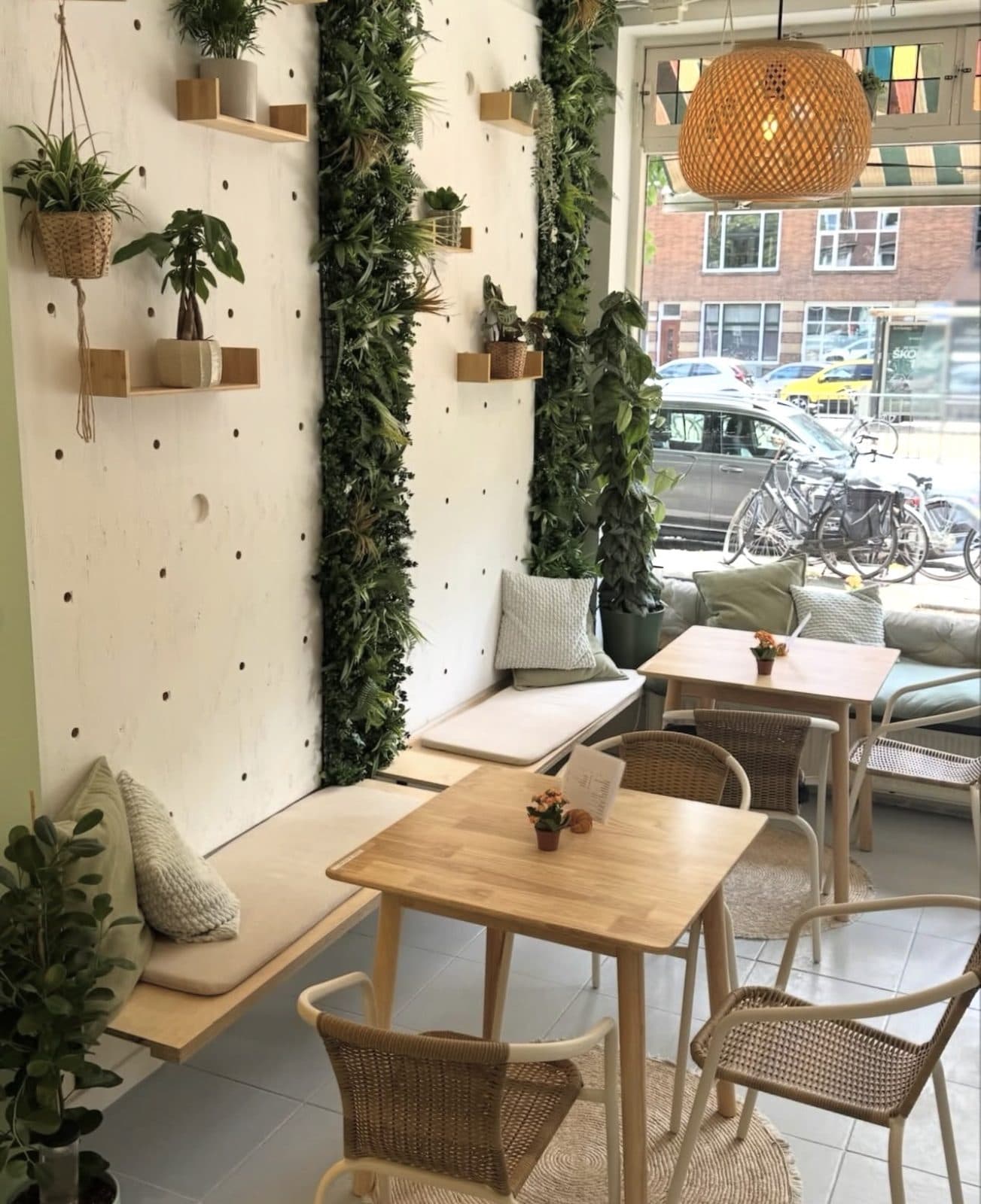 Het interieur van Coffee Garden — lichte houten tafels, planten en veel daglicht